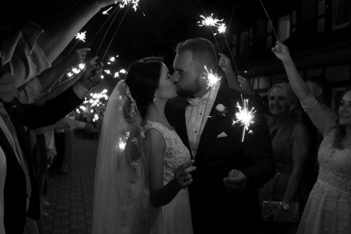 Couple kiss over sparklers in blog post about wedding guest entertainment. 