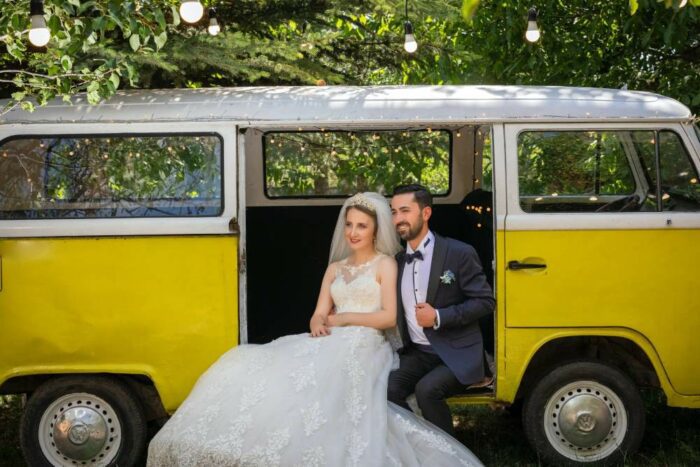 Couple sit inside yellow VW campervan for travel themed wedding, for blog about wedding guest entertainment.